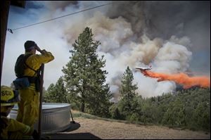 A DC-10 Air Tanker makes a drop on the Sand Fire at the middle fork of the Cosumnes River in Northern California as firefighters standby to protect a home.