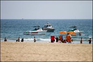 Lifeguard rescue boats patrol off the shore at Venice Beach on Sunday in Los Angeles. A 20-year-old man died Sunday after lightning struck 13 people at a popular Los Angeles beach and a golfer on Catalina Island during rare summer thunderstorms that swept through Southern California, authorities said.