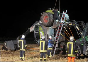 Firefighters try to set up a mechanical digger on a field near Isselburg, western Germany Tuesday. German authorities say a man was killed and several others were injured when the digger tipped over and hit them during a so-called Cod Water Challenge, a dare that has been spreading on Facebook. 