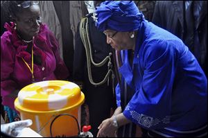 Liberia President  Ellen Johnson Sirleaf, right, demonstrates to people how to wash their hands properly in order to prevent the spread of the Ebola virus, during  Independence Day celebrations in the city of Monrovia, Liberia, Saturday.