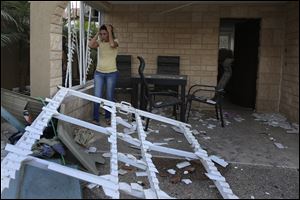 A woman looks at the damage from a rocket fired from Gaza which landed in the middle of a residential neighborhood Thursday in the city of Kiryat Gat, Israel.