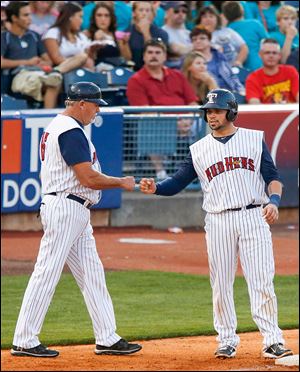 Mud Hen’s manager Larry Parrish, left, fist-bumps Manny Pina on third base during a recent game. Toledo trails wild-card leader Pawtucket by 7½ games with 28 games to go this season.