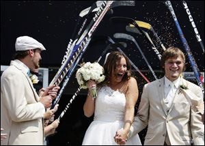 Ben and Courtney Sikkenga exit the Lakeshore Ice Center after their wedding in Fruitport Township, Mich.