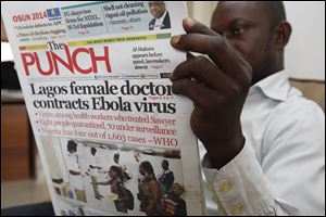 A man reads a local newspaper with headline news about a Lagos female doctor contracts Ebola Virus, in Lagos, Nigeria, Tuesday.
