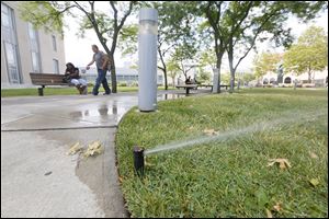 Sprinklers water the lawn at the Main Toledo-Lucas County Library downtown on Wednesday.