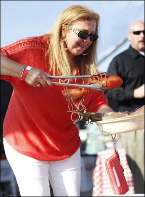 Diana Dettman picks up a lobster to put on her plate at the Toledo Chamber Clambake held at Hollywood Casino Toledo.