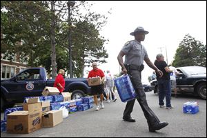 Sgt. Chris Fitzgerald, center, and other police officers and volunteers load water into citizens' cars at Waite High School.