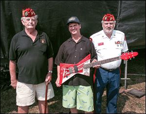 Mike Mori, director of sales for The Blade, flanked by Ronald Schramm, left, and Bob Baker of the Blue Diamonds Detachment, Marine Corps League, holds a guitar signed by Dennis DeYoung of Styx and the group War. The guitar was raffled off during the rib-off to raise money for the Marine Corps League.