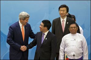 U.S. Secretary of State John Kerry, left, shakes hands with Vietnam Foreign Minister Pham Binh Minh, second left, as South Korea's Foreign Minister Yun Byung Se, third left and Myanmar Foreign Minister Wunna Maung Lwin, foreground right watch as they prepare to pose for a group photo before commencing 4th East Asia Summit.