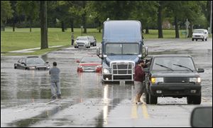 Stranded motorists look over flooded vehicles, Monday,   in Dearborn, Mich. The Michigan State Police issued an advisory Monday evening, urging drivers to avoid non-essential use of all metro Detroit freeways after heavy rain and thunderstorms left roads flooded and impassable.