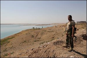 A Kurdish peshmerga fighter stands guard near the Mosul Dam at the town of Chamibarakat outside Mosul, Iraq, on Sunday. 