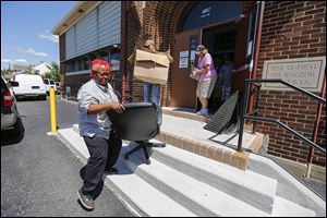 Jerrita Baker of Toledo carries out a chair she bought during an auction at the former Imani Learning Academy. It was one of the area charter schools that closed at the end of the academic year, and furniture and supplies were auctioned off to pay off their debts.