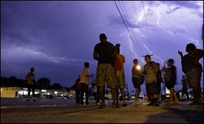 Protesters stand in the street as lightning flashes in the night sky in Ferguson, Mo. on Wednesday.