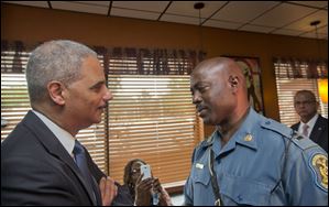 Attorney General Eric Holder speaks with Capt. Ron Johnson of the Missouri State Highway Patrol at Drake's Place Restaurant, Wednesday in Ferguson, Mo.