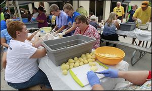 Volunteers peel potatoes — again — for potato salad at the festival after the first 1.5 ton-batch stored in a trailer was destroyed by fire.