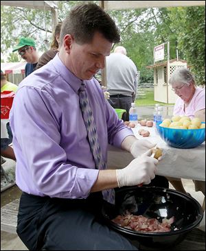 Mike Speweik takes a break from work to peel potatoes for potato salad at Oak Shade Grove.
