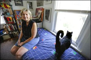 Lylanne Musselman sits with her cat near the window where burglars broke into her home. It took police about four hours to respond to her call.