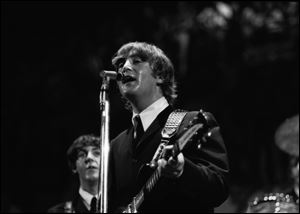 In this 1964 photo made by Walt Burton and provided by Christopher Hoeting, John Lennon, front, and Paul McCartney, of the Beatles, perform during a concert in Cincinnati.