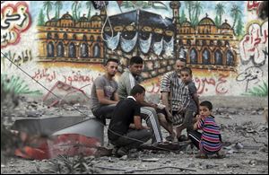 Palestinians rest amid the rubble of the 15-story Basha Tower that was leveled in early morning Israeli airstrikes, in Gaza City.