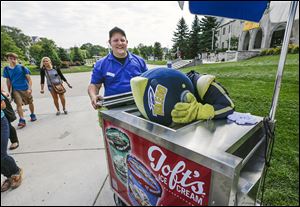 Aramark employee Mark Hupp laughs as University of Toledo mascot Rocky the Rocket tries to stick his head into an ice cream freezer to cool off. Mr. Hupp was passing out ice cream Tuesday near the Student Union as temperatures hit 90 for the first time this month and the fourth time this year.