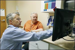 Dr. Mark Cockley confers  with one of his patients, John Petty of Perrysburg, in his office in Swanton.