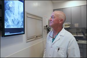 Urologist Dr. Emmett Boyle studies an X-ray of blocked kidneys and stents. He is a member of ProMedica Genito-Urinary Surgeons Inc. in Toledo. The center joined ProMedica in 2013.