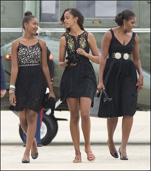 First lady Michelle Obama, right, and her daughters Sasha, left, and Malia, walk across the tarmac before boarding Air Force One prior to their departure from Andrews Air Force Base.