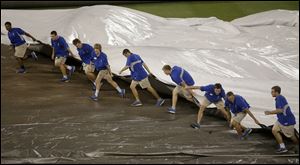 Members of the grounds crew  pull the tarp on the field during a rain delay in the 10th inning Sunday in Kansas City. Cleveland grabbed a 4-2 lead on pinch-hitter Lonnie Chisenhall’s two-out, two-run double, but rain prevented the teams from playing the bottom half of the inning. It was shelved after a 58-minute delay.