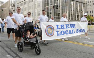 Members of the International Brotherhood of Electrical Workers Local 245 march in the Toledo Labor Day Parade. On Monday, thousands of union members marched through downtown past streets crowded with area residents and several dozen politicians.