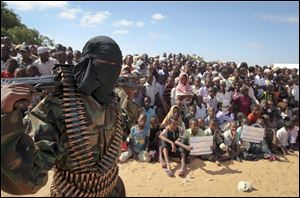 In this Feb. 13, 2012 file photo, an armed member of the militant group al-Shabab attends a rally in support of the merger of the Somali militant group al-Shabab with al-Qaida, on the outskirts of Mogadishu, Somalia. 