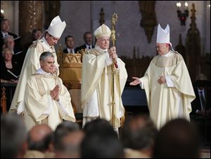 Archbishop Dennis Schnurr, left, and Archbishop Carlo Maria Vigano, right, present the crosier to Bishop Daniel E. Thomas during his installation ceremony at Our Lady, Queen of the Most Holy Rosary Cathedral today.