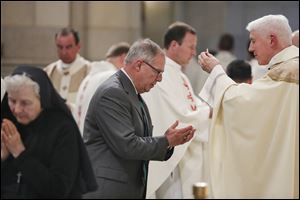 Mayor D. Michael Collins receives communion from the Most Reverend Daniel E. Thomas during his installation ceremony.