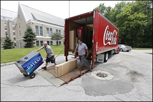 University of Toledo employees Chris Graham, left, and Bob Guerrero unload a water cooler to be placed in Horton International House as Coca-Cola products replaces Pepsi.