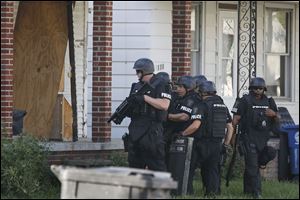 Police prepare to enter a vacant home to search for two suspects who fled into the dwelling  at 1137 Earl St. in Toledo, where the K-9 officer was shot on Wednesday.
