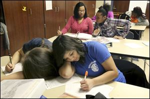 Woodward sophomores Alejandra Jimenez, 16, bottom left, and Reana Barboza, 15, lean against one another as they each write during a college prep class Jan. 27.