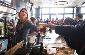 Tiffany Wicks serves up a brew at the packed Fleetwood Tap Room during opening day festivities for the Toledo Mud Hens today.