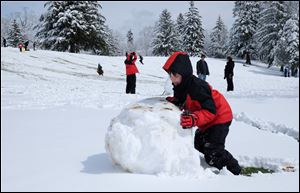 Vincent Kibler, 8, of Samaria, Mich., struggles to push a snow ball in preparation for a big snowman at Ottawa Park in Toledo.