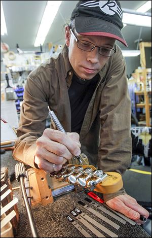 Guitar tech Zack Green of Temperance signs a guitar at Reverend Guitars in Sylvania Township on Tuesday.