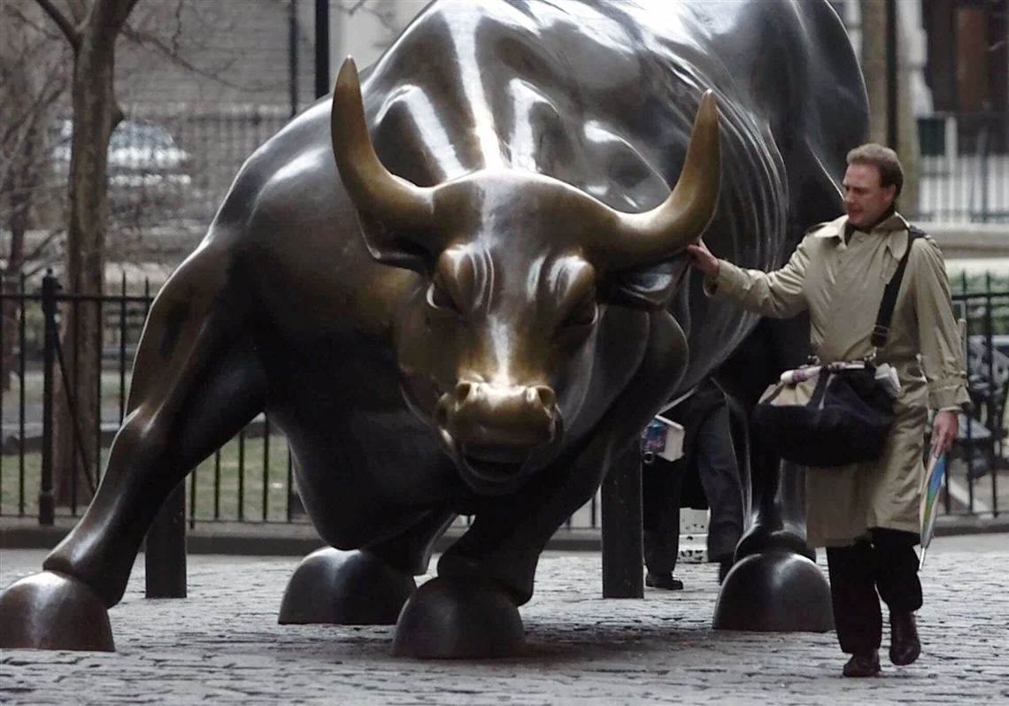 A businessman touches the bronze bull in the center of Broadway. The Nasdaq closed at another record high Thursday.