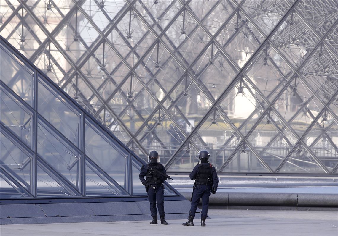 Police officers patrol at the pyramid outside the Louvre museum in Paris.