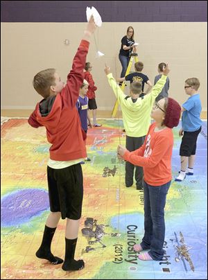 Fifth graders Taylor Lewis, left, and Alexandria Ybarra parachute a scientific payload down to the planet surface of Mars at Wayne Trail Elementary in Maumee. This was part of Maumee's STEM curriculum. 