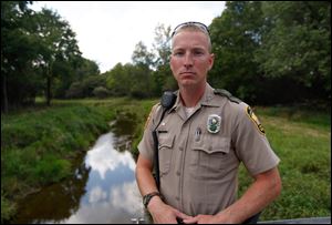 Ohio Division of Wildlife officer Anthony Lemle, next to Beaver Creek near West Jefferson, Ohio on August 23. Fish in the creek were killed after a significant rain event flooded manure into the creek.  