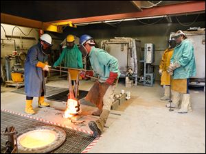Diana Williams, left, a senior from Toledo, carries the molten bronze with instructor Jerod Christy, third from left, at the University of Toledo's art foundry. Also pictured are Kara Thornton, sophomore, from Boston, second from left; Natassja Gresham, a sophomore from Toledo, fourth from left, and Taylor Kos, a senior from Toledo.