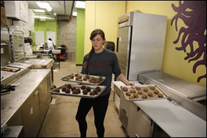 In this Friday, Sept. 15, 2017, photo, Rose Neukam juggles three sheets of cookies at Baked, in Bloomington, Ind. On Tuesday, Oct. 31.