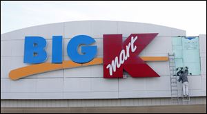 An employee works on the sign at the BIG Kmart store on Navarre Avenue in Oregon on Friday. The store is scheduled to close in January putting nearly 75 employees out of work.