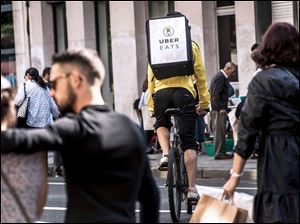 A cycle courier for meal delivery service Uber Eats rides past in Lille.