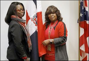 Cynthia Arias, left, poses for a photograph with her mother Celeste Felix-Taylor, the manager of the South Branch Library, after Ramon Gomez presented a Dominican Flag to the library Thursday at the McMaster Center in the main branch of the Toledo Lucas County Public Library in downtown Toledo.