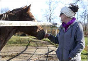 Air Force veteran Amanda Hardy, of Maumee, greets a horse at HOOVES (Healing Of Our Veterans Equine Services) in Ottawa Lake, Mich.