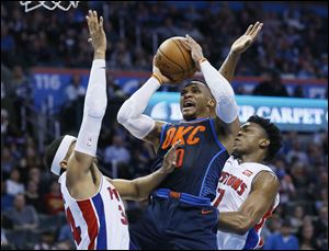 Oklahoma City Thunder guard Russell Westbrook puts up a shot between Tobias Harris, left, and Stanley Johnson of the Detroit Pistons.
