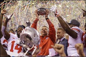 Ohio State coach Urban Meyer holds the trophy after Ohio State defeated Wisconsin 27-21 in the Big Ten championship game. Winning the game triggered a $100,000 bonus in Meyer's contract with the school.